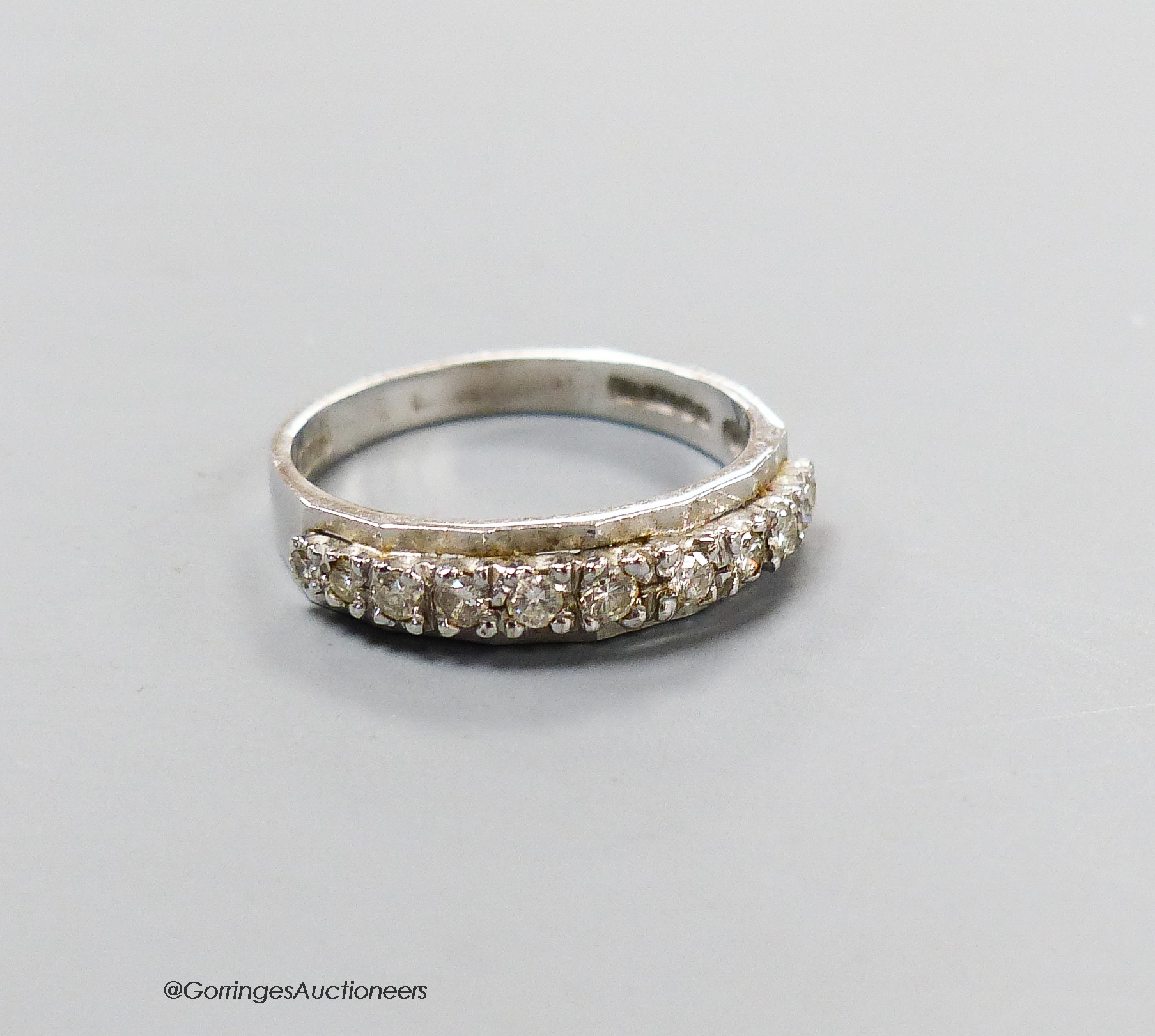 A modern 18ct white gold and eleven stone diamond chip set half eternity ring, size M, gross 2.8 grams.